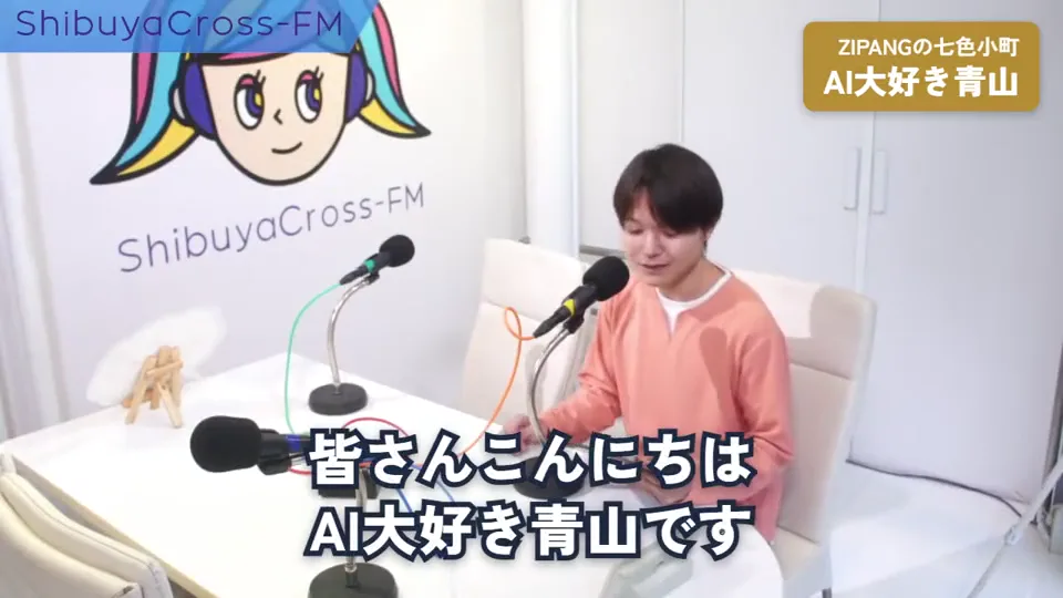 ラジオのスタジオで、話し手がタブレットを持ってマイクに話す。「皆さんこんにちは、AI大好き青山です」から、今日の話のテーマと進め方を話す。話す言葉の字幕が出る